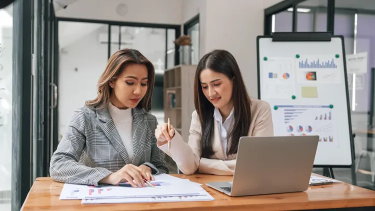Two young pretty asia business woman in suit talking together in modern office workplace, Thai woman, southeast asian